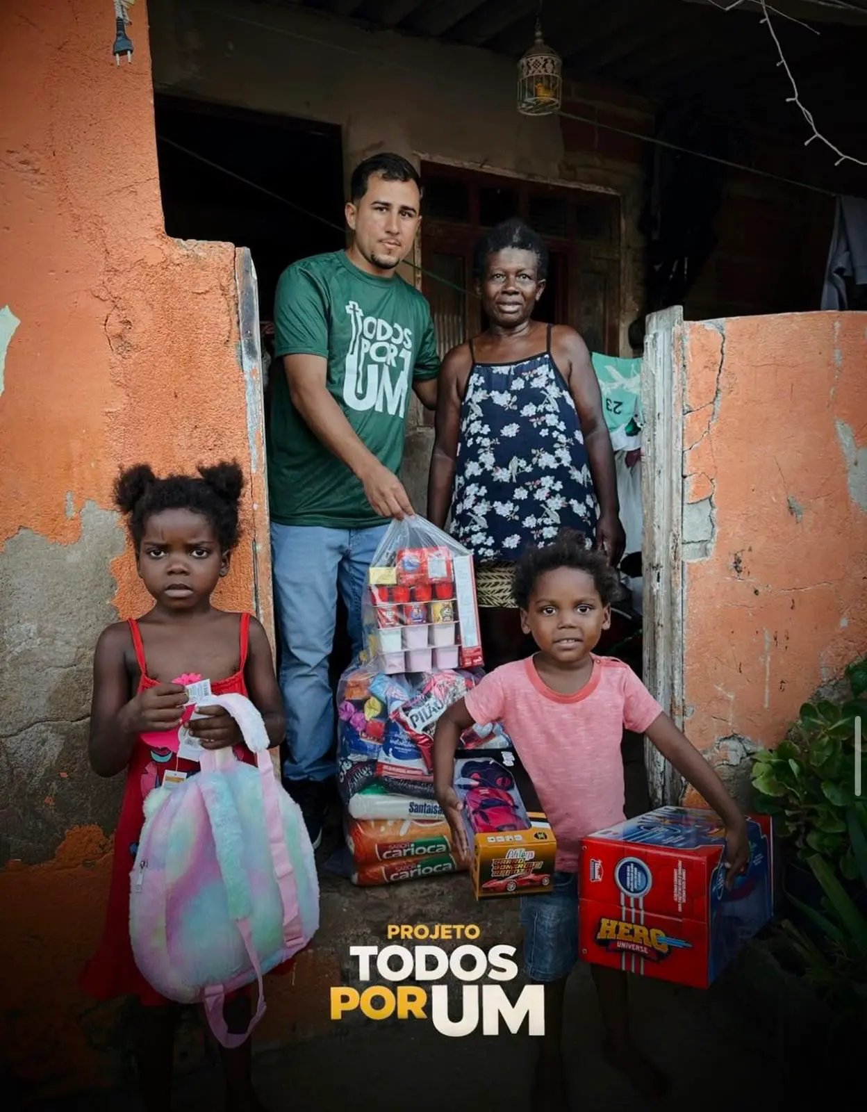 Voluntário da Todos Por Um entregando cesta básica e presentes a uma família